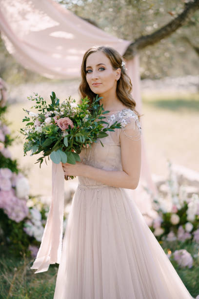 istock Bride with flowers stands near a tree 1356531108