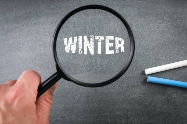 istock Winter. Text and magnifying glass on a black chalkboard 1356531798