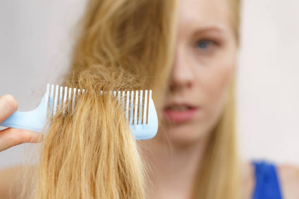 Blonde girl combing her long messy hair stock photo