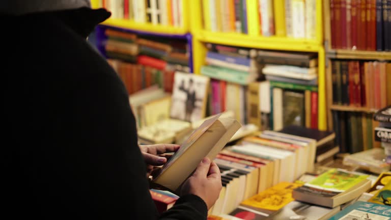 Young man looking at old book in second-hand bookshop, Vintage books for sale on a market stall in Portobello Road Flea Market