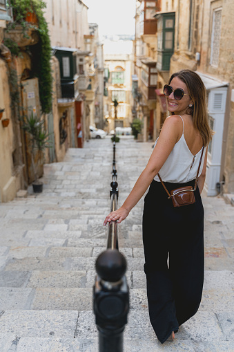 picture from the back of a beautiful young woman walking on the streets of La Valletta Malta