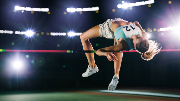 High Jump Championship: Professional Female Athlete on World Championship Successfully Jumping over Bar. Shot of Competition on Stadium with Sports Achievement Experience. Determination of Champion. High Jump Championship: Professional Female Athlete on World Championship Successfully Jumping over Bar. Shot of Competition on Stadium with Sports Achievement Experience. Determination of Champion. long jump stock pictures, royalty-free photos & images