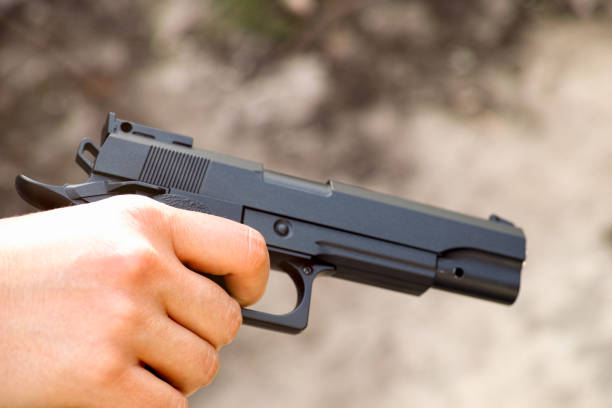 A Realistic black airsoft gun in person hand. Closeup