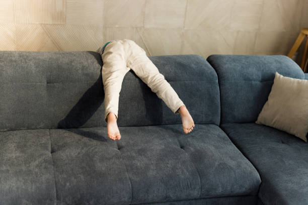 Unrecognizable kid having fun on sofa in the living room. Copy space.
