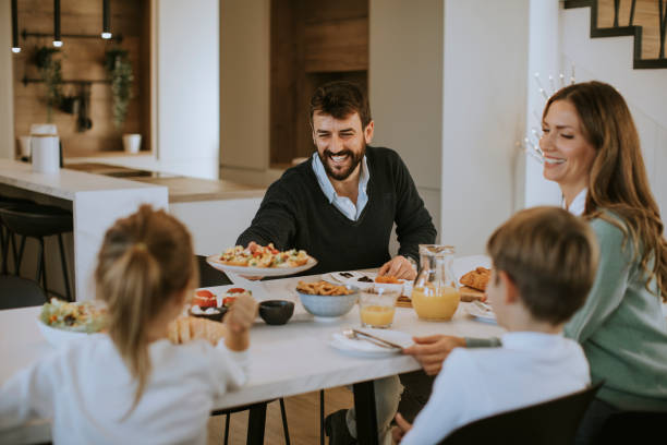 istock Young happy family talking while having breakfast at dining table 1356544611