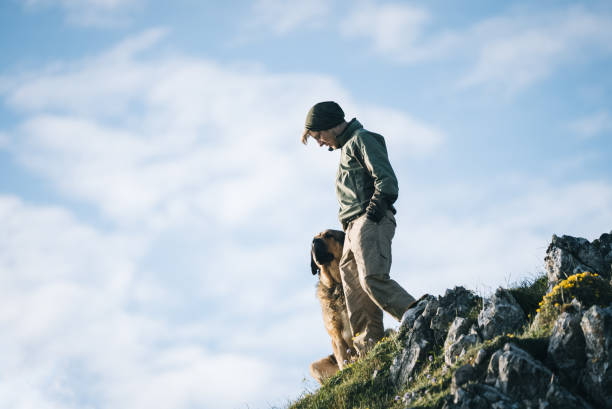 istock Young man and dog walk down mountain ridge 1356544925