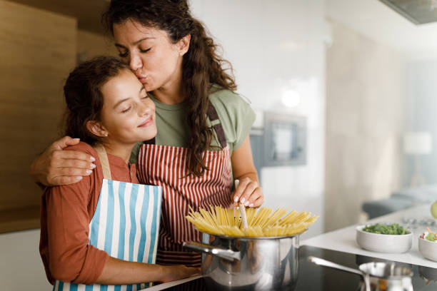 Loving single mother and her daughter making lunch in the kitchen.