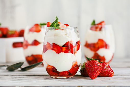Healthy breakfast of strawberry parfait made with fresh fruit, and yogurt over a rustic white table