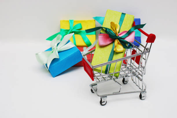 istock Shopping cart and four multi-colored gift boxes on a white background. 1356547649