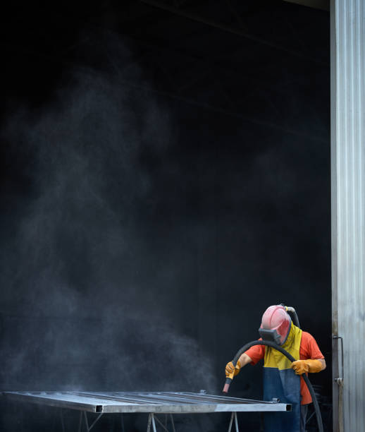 istock Operator of sandblasting machine polishing metal at workshop 1356547864