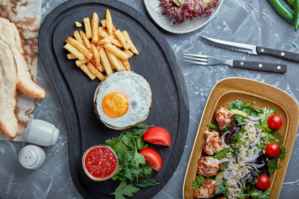 istock Beef steak with egg and salad from greens and vegetables. Wooden background, table setting, fine dining 1356550805