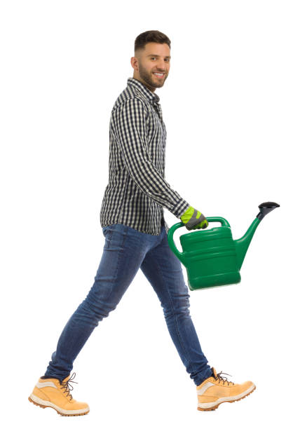istock Gardener is walking with green watering can. Side view. Studio shot, isolated. 1356553057
