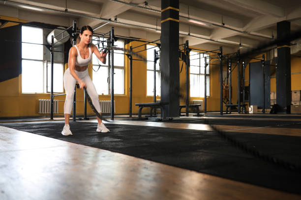 istock Fit woman using battle ropes during strength training at the gym. 1356554556