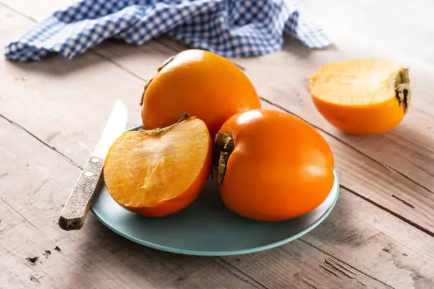 Fresh persimmon fruit on wooden table