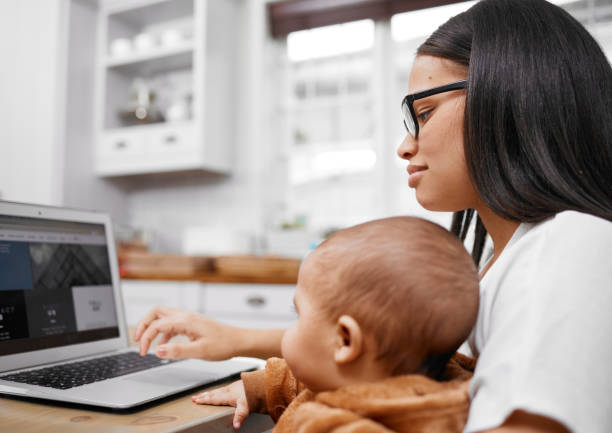 istock Shot of a young mother using a laptop while holding her son at home 1356555825