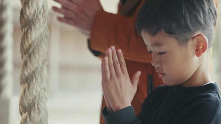 CU- Grandfather praying with his grandson at a Japanese temple