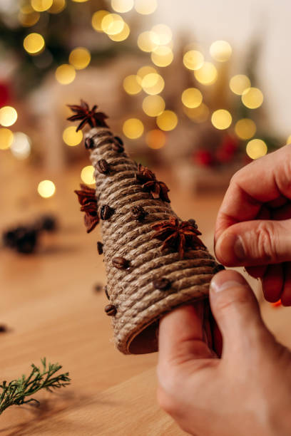 decoración de un árbol de navidad hecho a mano de cartón y cuerda con granos de café y anís estrellado, manos de cerca. navidad, año nuevo y concepto ecológico. - badian fotografías e imágenes de stock