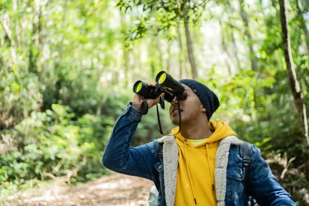 Young man using binoculars during hiking