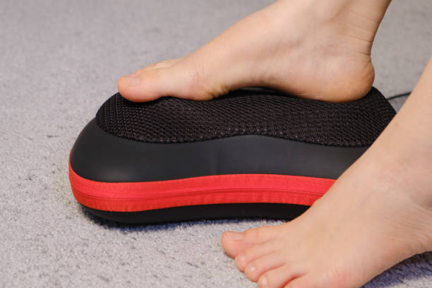 istock Women's legs and electric automatic massager, foot massage with a massage pillow. 1356560249