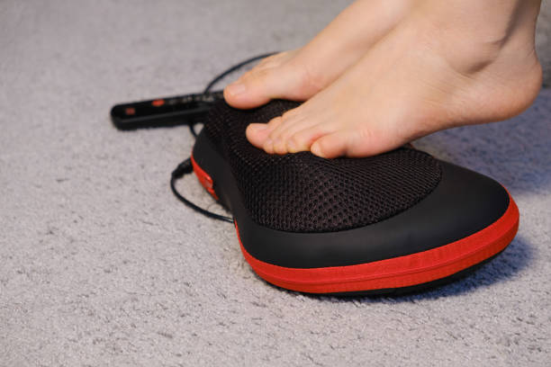 istock Women's legs and electric automatic massager, foot massage with a massage pillow. 1356560263