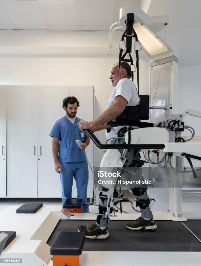 Senior man walking with an exoskeleton while doing physiotherapy Senior Latin American man walking with an exoskeleton while doing physiotherapy after an injury Healthcare And Medicine Stock Photo