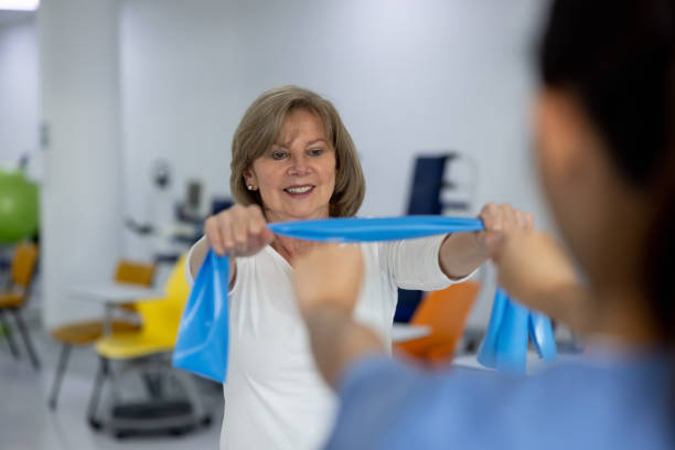 istock Happy woman using a resistance band in physiotherapy 1356562164