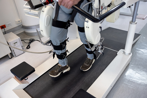 Close-up on a man using a powered exoskeleton during his physical therapy at a rehab center