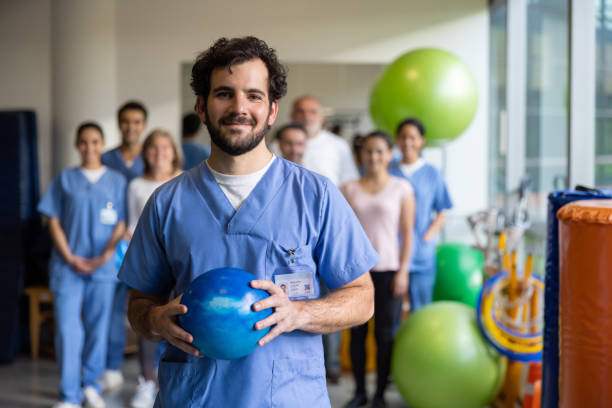 physiothérapeute travaillant dans un centre de réadaptation avec un groupe en arrière-plan - occupational therapy photos et images de collection