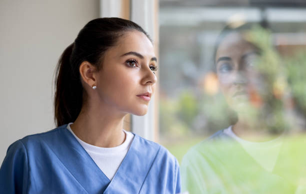 istock Nurse looking through the window of a hospital while working 1356562790