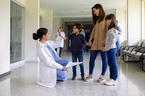 Happy Latin American female doctor high-fiving with a boy at the hospital