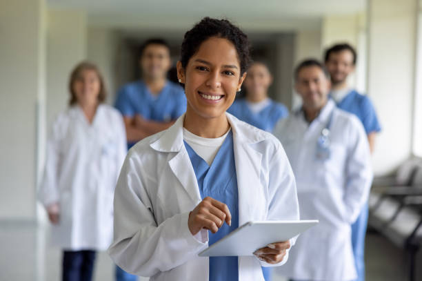 happy doctor leading a team of healthcare workers at the hospital - senior adult happiness computer looking at camera imagens e fotografias de stock