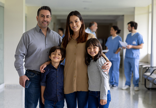 Portrait of a happy Latin American family smiling at the hospital while looking at the camera - healthcare and medicine