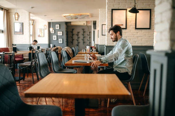 istock Businessman using smart phone and drinking coffee in cafe. 1356563045