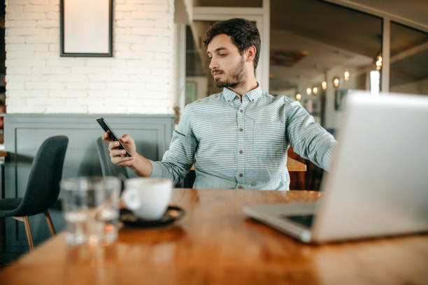 istock Businessman using smart phone and drinking coffee in cafe. 1356563340