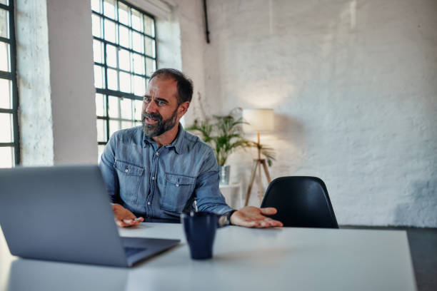 Man during online therapy session Middle age man having a counseling session with a psychologist using a video conferencing tool melancholy computer support specialist stock pictures, royalty-free photos & images