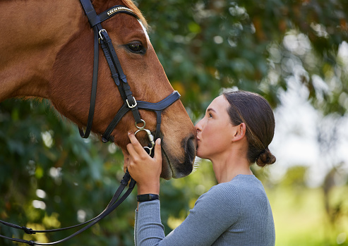 Horse and girl share an emotional moment in close up shot as they appear to kiss.