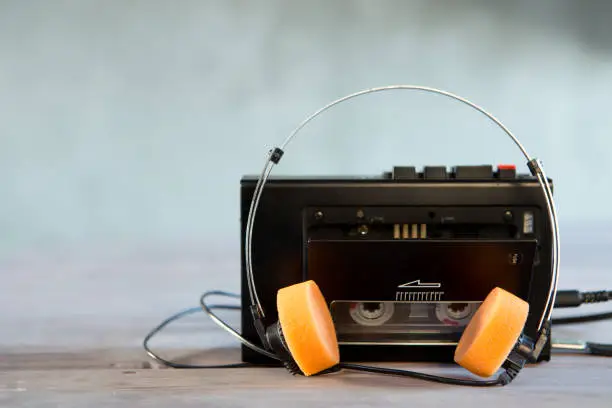 Old portable cassette player and headphones on a abstract background. Vintage advertisement style