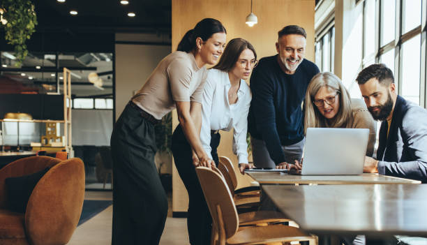 istock Group of businesspeople using a laptop together 1356570998