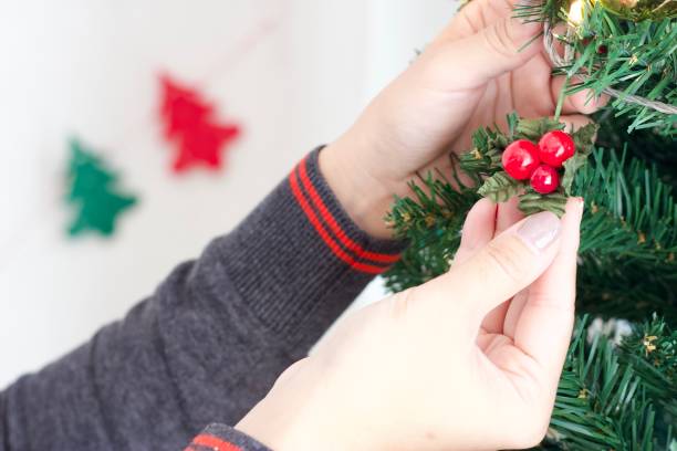 istock Asian female hand decorating replica cherries on Christmas Tree with blurred red and green color decorative Christmas tree. 1356572321
