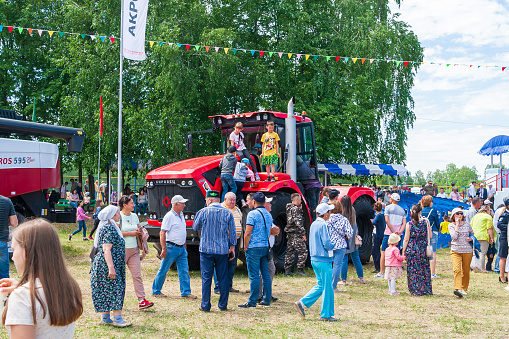 Ufa, Chishmy, Russia, 06.05.2021. National Tatar-Bashkir holiday Sabantuy. Exhibition of agricultural machinery. Children climbed onto the Kirovets tractor.