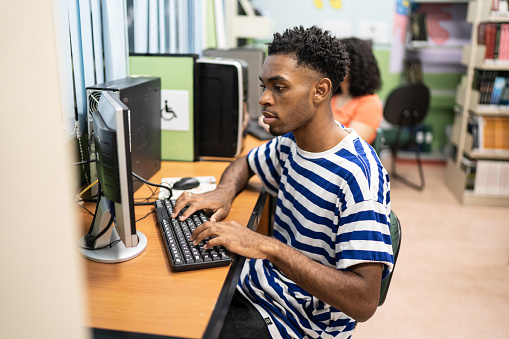 Young man using computer in a library