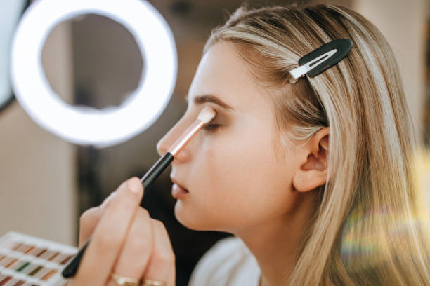 Make up and beauty work Makeup process. Professional artist applying make up on model face. Close up portrait of beautiful blonde woman in beauty saloon. makeup artist stock pictures, royalty-free photos & images
