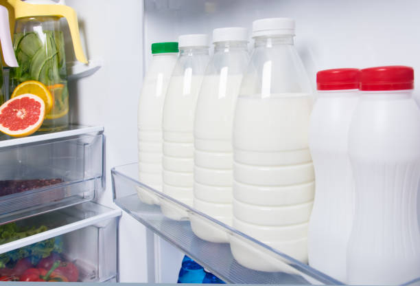 against the background of a white open refrigerator, bottles with milk in the door on the shelf against the background of a white open refrigerator, bottles with milk in the door on the shelf Milk stock pictures, royalty-free photos & images