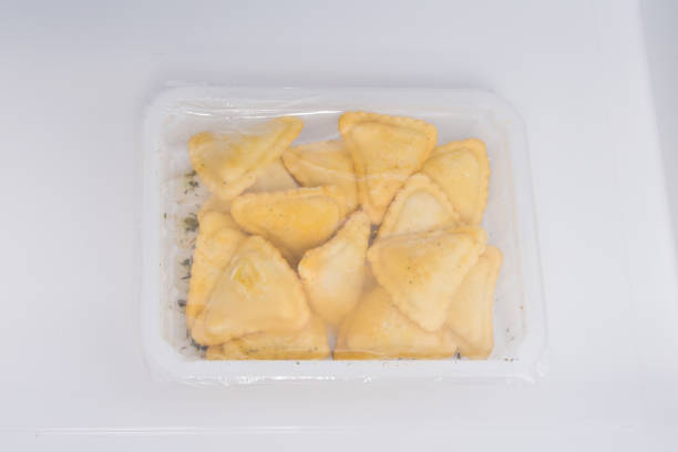 istock frozen fast food for deep-frying in vacuum packaging, triangles with meat, on a white background 1356578080