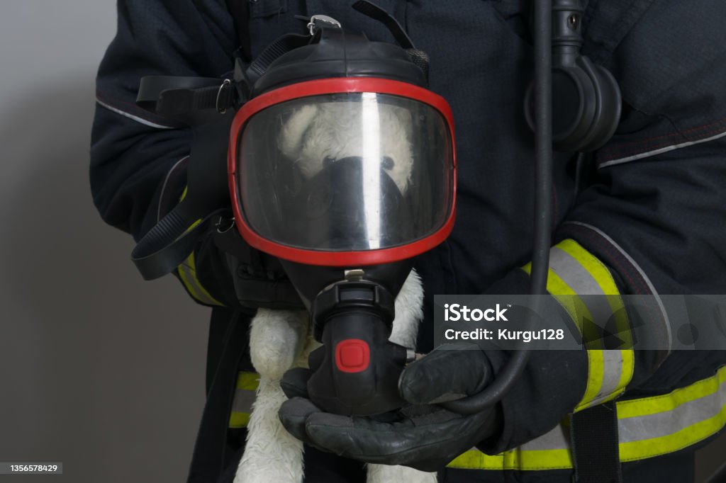 a firefighter put a breathing mask on a child's toy, a rescued teddy bear A Helping Hand Stock Photo