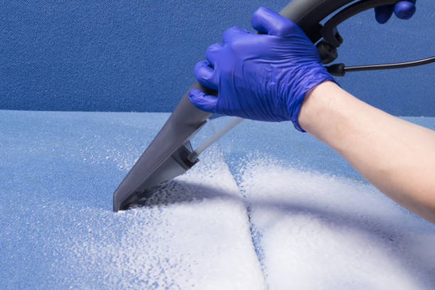istock hand in a protective glove, collecting dirt from a blue sofa, using a washing vacuum cleaner and foam, close-up 1356578450