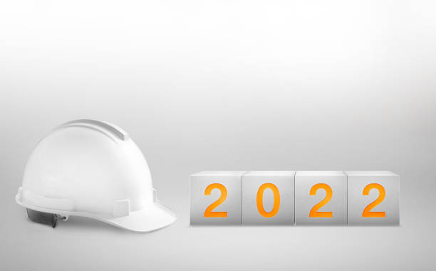 feliz ano novo 2022 construção e indústria.capacete branco e um cubo de concreto numerado em fundos brancos. - year block cube new years eve - fotografias e filmes do acervo