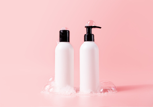 Shampoo and hair conditioner bottle with soapy bubbles. Plastic white packing with black cap beauty hair care cosmetic packaging mockup