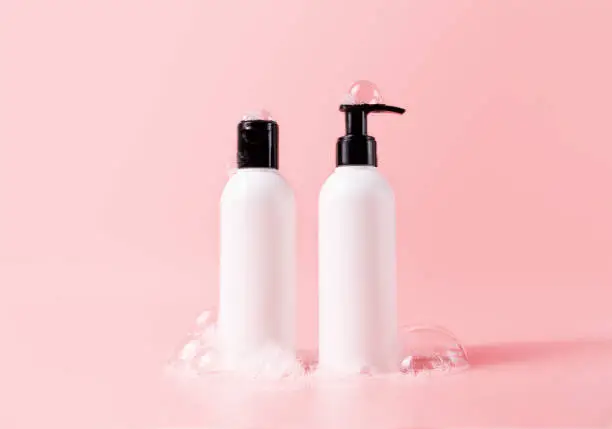 Photo of Shampoo and hair conditioner bottle with soapy bubbles. Beauty hair care cosmetic packaging mockup