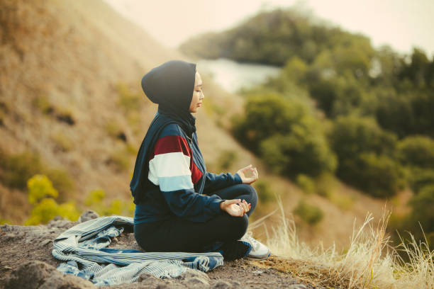 meditação de mulher muçulmana asiática na colina observando a praia ao nascer do sol - lake tranquil scene landscape zen like - fotografias e filmes do acervo